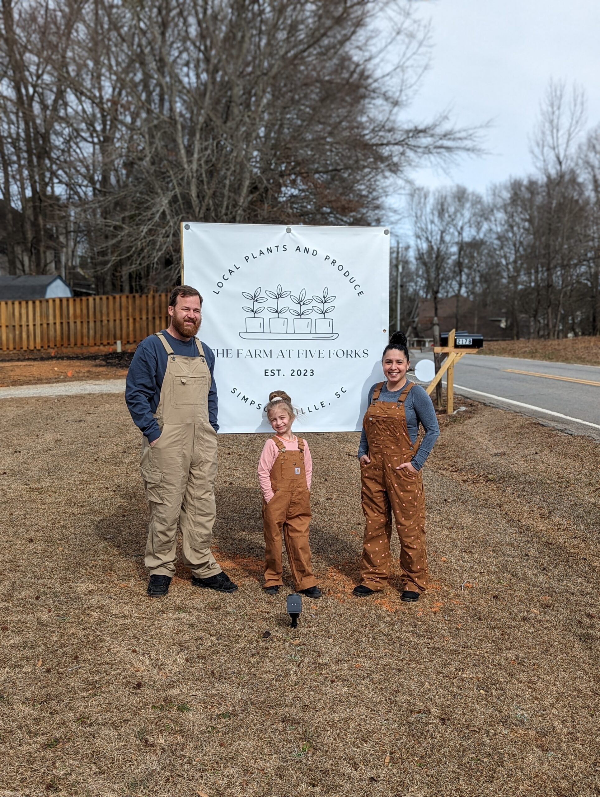 farm at five forks family in front of the farm's sign